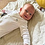Noah is registered to the contest to win money with this photo: baby, smiling, white_onesie, blanket, plush_toy, indoor, carpet, happy, infant, cute, child, portrait, lying_down, soft_toys, cozy, person, closeup, baby_clothing, warm_lighting, relaxed