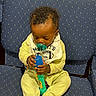 Joel is registered to the contest to win money with this photo: baby, child, pacifier, toy, microphone, onesie, bib, chair, blue, pattern, seated, infant, cute, indoor, clothing, holding, focused, person, young_child, small