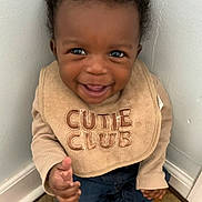 Joel joined the competition — help win amazing prizes! baby, child, smiling, bib, clothing, indoor, carpet, corner, cute, portrait, happy, person, young, sitting, face, head, hand, footwear, denim, expression