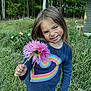 Kalani is registered to the contest to win money with this photo: casual_clothing, child, cute, daylight, flower, garden, girl, grass, greenery, happy, long_hair, nature, outdoor, person, pink_flower, playful, portrait, rainbow_shirt, smiling, trees