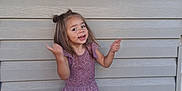 Kalani is registered to the contest to win money with this photo: barefoot, casual_clothing, child, cute, daylight, expression, full_body, girl, happy, joy, long_hair, outdoor, playful, posing, purple_outfit, smiling, standing, tile_floor, wooden_wall, young
