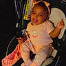 baby, black_background, blanket, car_seat, child, clothing, comfortable, cute, happy, headband, indoor, infant, orange, pajamas, person, pink, seat, smiling, tongue_out, toy