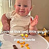 baby, child, toddler, high_chair, sitting, smiling, waving, face, portrait, indoor, kitchen, refrigerator, highchair_tray, snacks, food, orange_food, crumbs, casual_photo, text_overlay, happy