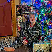 Nicholas is registered to the contest to win money with this photo: child, smiling, pajamas, barefoot, christmas_tree, christmas_lights, presents, gift_wrap, holiday, indoor, floor, decorations, festive, home, door, rug, happy, seated, celebration, seasonal