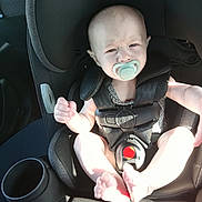 Remington is registered to the contest to win money with this photo: baby, pacifier, car_seat, child, infant, seatbelt, straps, car_interior, sunlight, shadow, face, feet, expression, sitting, safety, young_child, person, closeup, transportation, seat