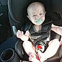 baby, pacifier, car_seat, child, infant, seatbelt, straps, car_interior, sunlight, shadow, face, feet, expression, sitting, safety, young_child, person, closeup, transportation, seat