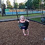 Remington joined the competition — help win amazing prizes! baby, swing, playground, wood_chips, child, outdoor, trees, fence, tennis_court, grass, sidewalk, summer, happy, fun, person, clothing, barefoot, daylight, park, seat