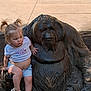 Clara joined the competition — help win amazing prizes! child, toddler, statue, orangutan, sculpture, outdoor, sidewalk, trash_can, shorts, tshirt, sandals, hair, pigtails, curious, hand, concrete, sunlight, shadow, nature, playful