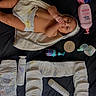 baby, infant, diaper, towel, baby_care, skin, hand, face, lying_down, product_bottle, baby_lotion, baby_powder, black_background, newborn, child, cute, baby_skin, baby_supplies, personal_care, sucking_fingers