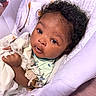 baby, baby_clothes, bed, bedding, blanket, child, close_up, cozy, curious, curly_hair, dark_skin, face, green_shirt, indoors, infant, lying_down, photography, plush_toy, portrait, stuffed_animal