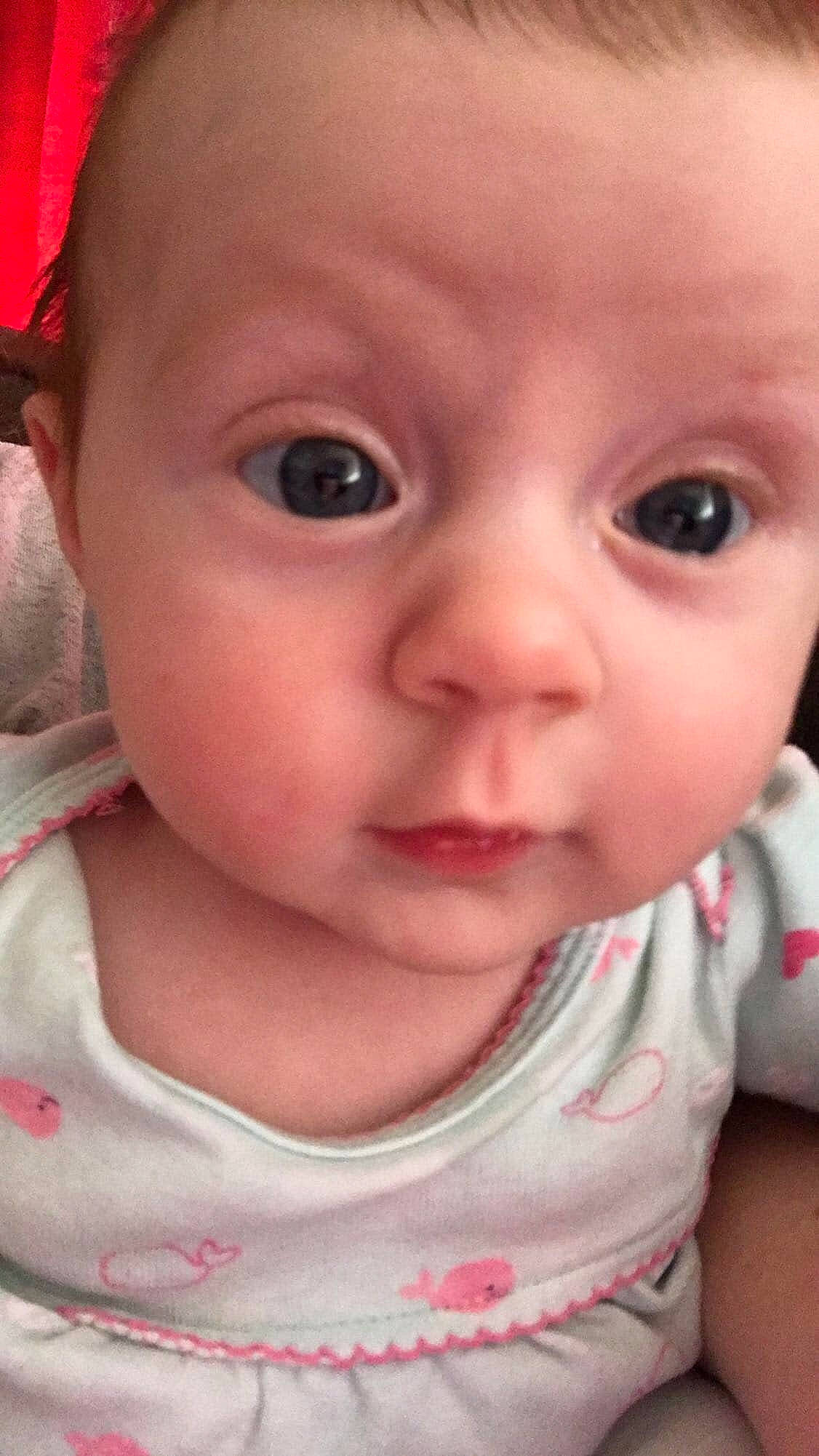 Lila is registered to the contest to win money with this photo: baby, baby_making_funny_faces, cheek, child, chin, close_up, eye, eyebrow, face, facial_expression, forehead, head, iris, lip, mouth, nose, person, pink, skin, smile