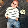 baby, child, crib, striped_shirt, denim_pants, smile, milestone_card, 4_months, wooden_crib, blanket, happy, infant, cute, portrait, socks, indoor, person, young_child, clothing, face