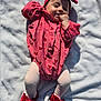 baby, infant, child, red_clothing, headband, bow, blanket, outdoor, sunlight, smiling, happy, lying_down, footwear, red_shoes, heart_pattern, tights, cute, one_person, small_child, playful