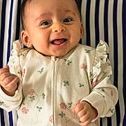 Giulia participe au concours pour gagner de l'argent avec cette photo : baby, infant, smiling, happy, face, clothing, onesie, floral_pattern, striped_background, lying_down, hand, cute, child, portrait, young, person, head, cheerful, hair_clip, closeup