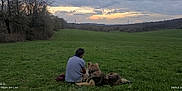 Pollux participe au concours pour gagner de l'argent avec cette photo : casual_clothing, clouds, companion, dog, evening, field, grass, hills, landscape, leisure, man, nature, outdoor, pet, relaxation, scenery, sitting, sky, sunset, trees