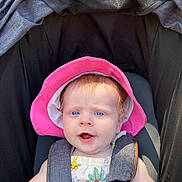Sara is registered to the contest to win money with this photo: baby, child, blue_eyes, pink_hat, stroller, sunhat, outdoor, infant, cute, summer_clothes, safety_harness, curious_expression, light_skin, sunlight, portrait, closeup, seat, baby_girl, happy, daytime
