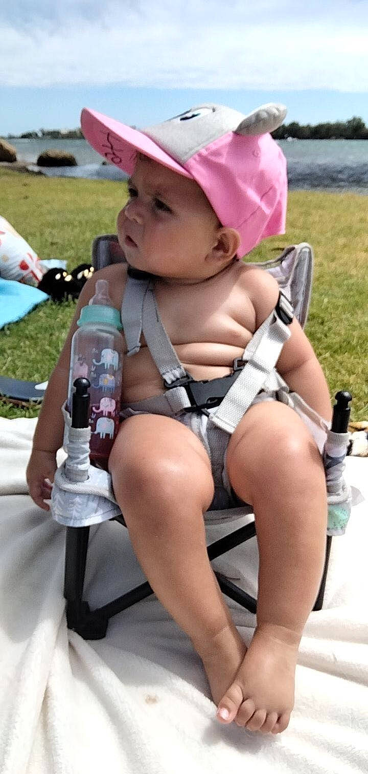 Cassius is registered to the contest to win money with this photo: baby, baby_toddler_clothing, bottle, cap, child, fashion_accessory, hat, headwear, human_leg, leisure, person, plant, plastic_bottle, recreation, sitting, summer, sun_hat, thigh, toddler, vacation