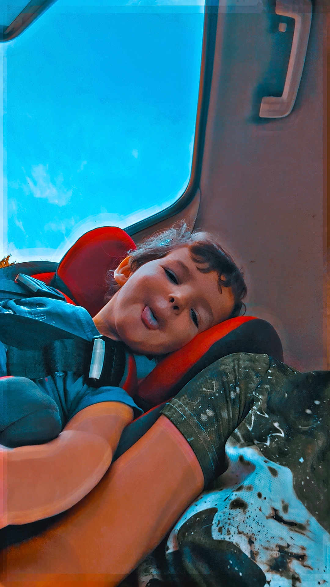 Logan a rejoint le concours — aidez-le/la à gagner de superbes lots ! child, car_seat, blue_sky, car_interior, seatbelt, tongue_out, playful, person, window, adult, casual_clothing, seat_handle, curly_hair, smiling, daylight, fun, travel, road_trip, cute, happy