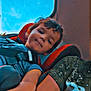 child, car_seat, smiling, blue_sky, window, seatbelt, car_interior, person, casual_clothing, short_hair, arm, paint_splatter, daylight, happy, young, portrait, indoor, seat, head, face