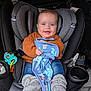 baby, car_seat, child, blue_eyes, orange_sweater, blanket, gray_booties, smiling, indoor, seatbelt, toy, car_interior, cute, infant, happy, clothing, portrait, holding, cozy, comfort