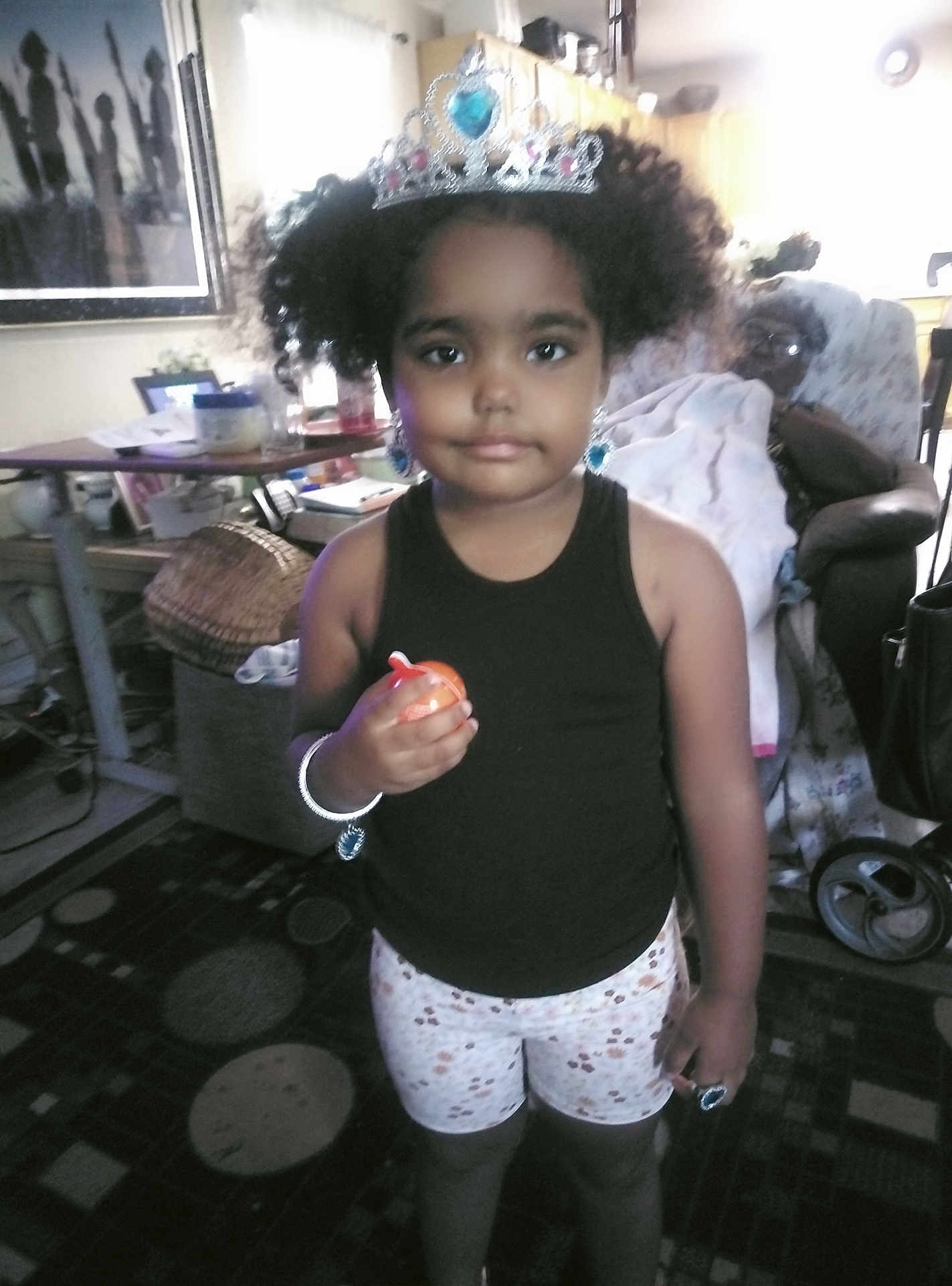 Myrackle is registered to the contest to win money with this photo: child, girl, crown, jewelry, black_tank_top, shorts, toy, living_room, rug, carpet, furniture, table, chair, person, indoor, portrait, curtains, window, bracelet, earrings