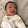 baby, newborn, infant, smile, face, onesie, winnie_the_pooh, clothing, cute, lying_down, blanket, soft_texture, child, portrait, happy, skin, head, person, sleepwear, young