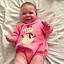 Aspen is registered to the contest to win money with this photo: baby, bed, child, chubby_cheeks, clothing, cozy, cute, face, hands, happy, indoors, infant, legs, lying_down, pink_onesie, skin, smile, snowman_print, soft_light, white_bedspread