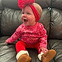 baby, brown_boots, candy_cane_pattern, cheerful, child, cozy, cute, happy, holiday_theme, indoors, infant, leather_couch, pink_sweater, portrait, red_headband, red_pants, sitting, small_hands, smiling, warm_clothing