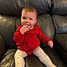 baby, child, red_clothing, white_tights, sitting, leather_couch, indoor, happy, smiling, cute, portrait, infant, fingers_in_mouth, casual, home, young_child, toddler, cozy, comfortable, playful