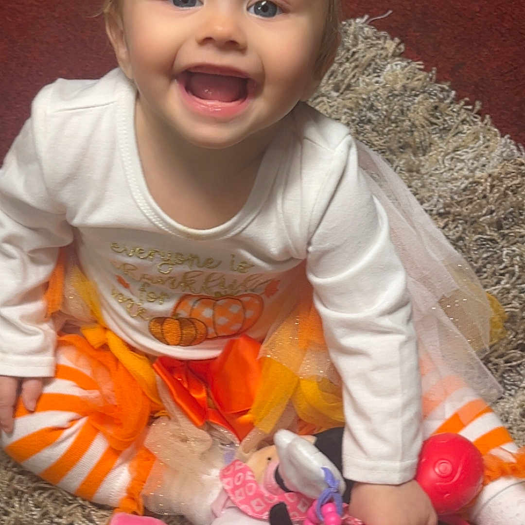 Mercy is registered to the contest to win money with this photo: autumn_colors, baby, bright, carpet, child, cute, festive, fun, happy, headband, indoor, minnie_mouse, orange_bow, playtime, sitting, smiling, striped_leggings, toddler, toy, white_shirt