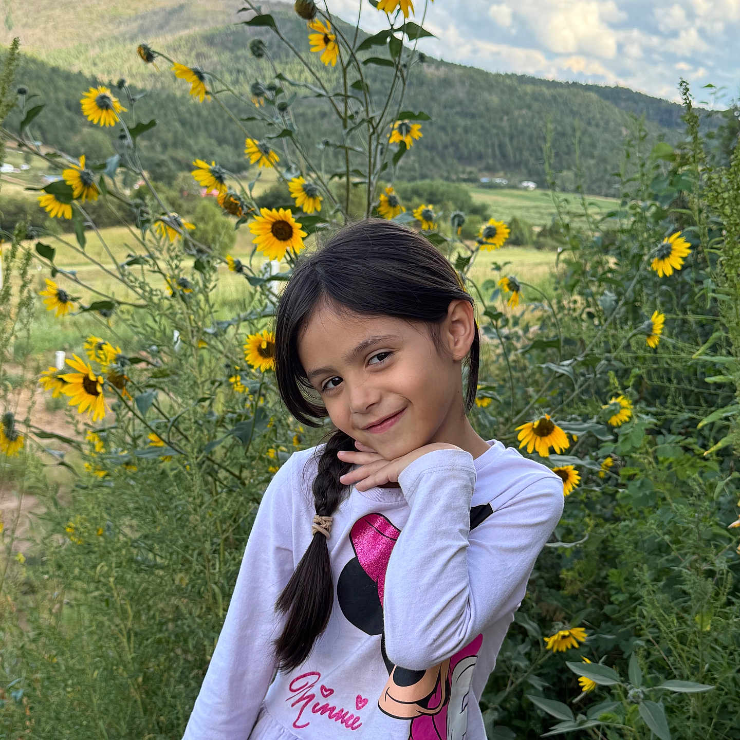 Heavenly Faith is registered to the contest to win money with this photo: braid, casual_clothing, child, clouds, daylight, field, flowers, girl, greenery, hill, long_sleeve, nature, outdoor, plants, playful, portrait, sky, smile, sunflowers, young