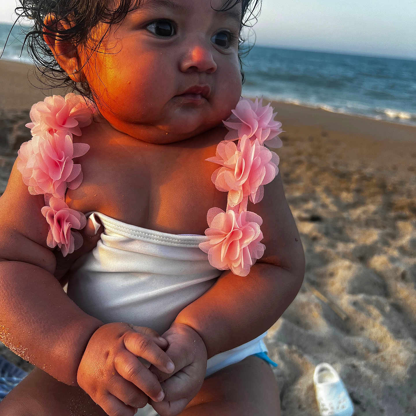 Selena joined the competition — help win amazing prizes! baby, beach, child, curly_hair, cute, footwear, golden_hour, hands, legs, ocean, outdoor, pink_flower, portrait, sand, sea, skin, summer, sunset, water, white_outfit