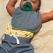 Brayden joined the competition — help win amazing prizes! baby, pacifier, bib, blue_clothing, striped_shirt, infant, lying_down, arms_stretched, soft_surface, cute, child, casual_wear, relaxed, indoors, portrait, smiling, young_child, small_person, sleepy, baby_garments