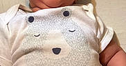 Brayden is registered to the contest to win money with this photo: baby, smiling, infant, onesie, bear_print, clothing, happy, face, skin, arm, cute, child, portrait, indoors, person, newborn, baby_girl, baby_boy, expression, lying_down
