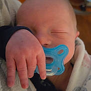 Xavier is registered to the contest to win money with this photo: baby, newborn, pacifier, hand, sleeping, blanket, infant, closeup, person, cute, soft, cozy, indoor, wrapped, peaceful, small, skin, head, fingers, resting