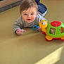 baby, child, infant, toddler, toy, turtle_toy, pacifier, playmat, mirror, reflection, smiling, crawling, floor, indoor, sunlight, clothing, sleeve, eyes, hair, happy