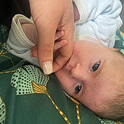 Naelya a rejoint le concours — aidez-le/la à gagner de superbes lots ! baby, infant, hand, finger, close_up, face, skin, eyelashes, blanket, fabric, pattern, green, white, person, newborn, resting, curious, soft, caring, tender