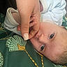 baby, infant, hand, finger, close_up, face, skin, eyelashes, blanket, fabric, pattern, green, white, person, newborn, resting, curious, soft, caring, tender