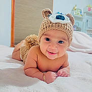Henry is registered to the contest to win money with this photo: baby, smiling, knitted_hat, bear_hat, diaper_cover, blanket, indoor, cute, child, portrait, soft_texture, lying_down, happy, infant, bracelet, warm_lighting, home, cozy, face, person