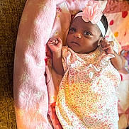 Journei is registered to the contest to win money with this photo: baby, blanket, child, cozy, curious, cute, floral_dress, flower, headband, indoors, infant, lying_down, newborn, person, pink_blanket, portrait, resting, small_hands, soft_fabric, toddler