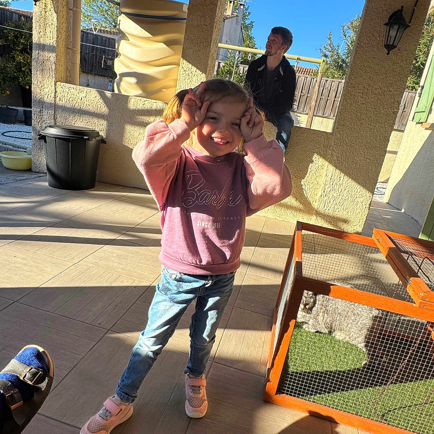 Clar a rejoint le concours — aidez-le/la à gagner de superbes lots ! animal, cage, casual, child, daylight, fence, girl, home, jeans, man, outdoor, patio, pet, playful, posing, shadows, smile, sneakers, sunlight, sweatshirt