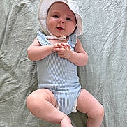 Alix a rejoint le concours — aidez-le/la à gagner de superbes lots ! baby, barefoot, blanket, blue_striped_clothing, child, cute, hands_clasped, happy, hat, indoor, infant, lying_down, playful, portrait, romper, skin, smiling, soft_lighting, sunhat, young