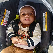 Genesis is registered to the contest to win money with this photo: baby, infant, child, car_seat, sitting, portrait, face, eyes, tongue, smiling, curious, clothing, jacket, pants, bear_design, headband, hands, indoor, photography,  안전