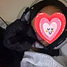 cat, black_cat, person, headphones, heart_sticker, face_cover, text_overlay, french_text, indoor, bedroom, bed, blanket, cozy, cuddling, pet, portrait, selfie, dark_fur, casual, gaming
