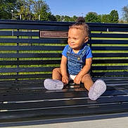 Terri'Jo is registered to the contest to win money with this photo: toddler, child, bench, outdoor, park, grass, trees, blue_sky, sunny, smiling, sitting, clothing, socks, daylight, nature, happy, casual, portrait, social_media, music_overlay