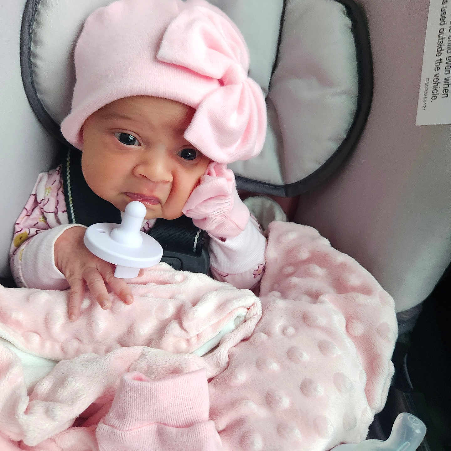Na'Hijah is registered to the contest to win money with this photo: accessory, baby, baby_bottle, blanket, car_seat, child, clothing, cozy, cute, face, hand, indoors, infant, newborn, pacifier, person, pink_hat, seatbelt, soft_texture, warm