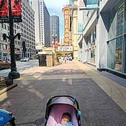 Na'Hijah is registered to the contest to win money with this photo: baby, stroller, sleeping, sidewalk, city, urban, buildings, skyscrapers, street, pedestrians, daytime, sunlight, sign, chicago, architecture, urban_life, transportation, cup, drink, relaxation