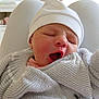 Mía participe au concours pour gagner de l'argent avec cette photo : newborn, baby, yawning, hat, knitwear, infant, person, sleepy, cozy, wrapped, closeup, soft_light, indoor, lap, blanket, cute, small, resting, child, warm