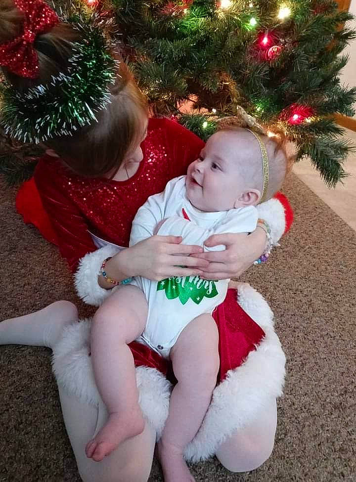 Savannah joined the competition — help win amazing prizes! baby, baby_toddler_clothing, child, christmas_decoration, christmas_ornament, christmas_tree, eye, facial_expression, fun, green, happy, head, human_body, lap, leg, person, plant, skin, standing, toddler