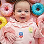 baby, background, child, colorful, cute, donuts, flowers, food, happy, infant, laying_down, pastel_colors, pink_clothing, playful, portrait, smiling, snack, sprinkles, sweet, toddler
